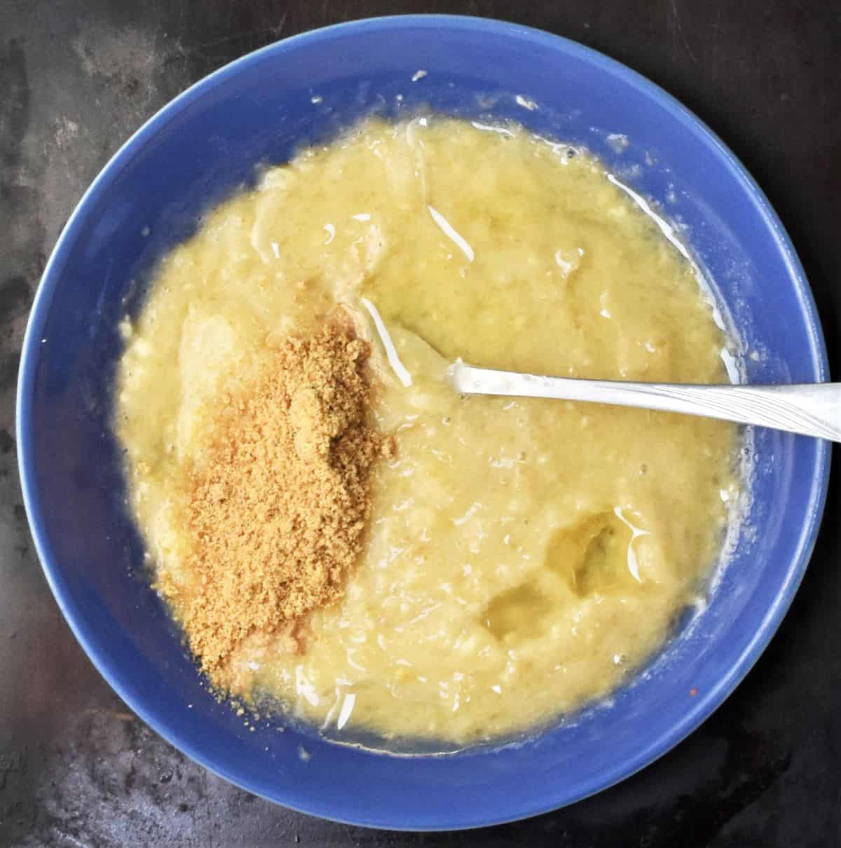 Mashed banana with flaxseed in blue bowl.