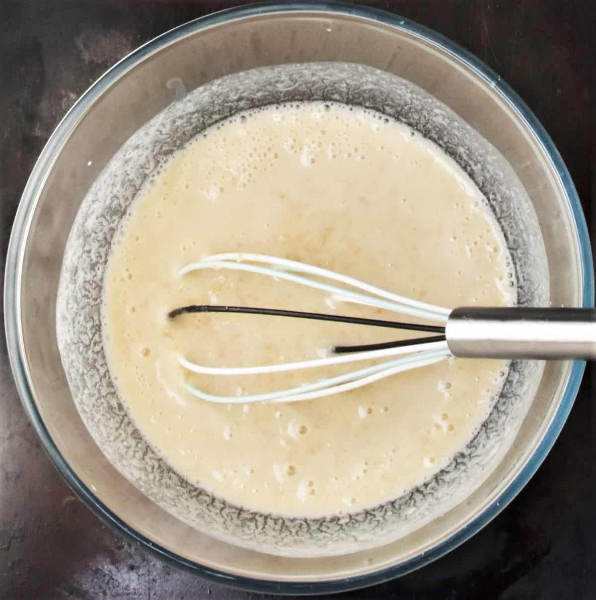 Making pancake batter in mixing bowl with whisk.