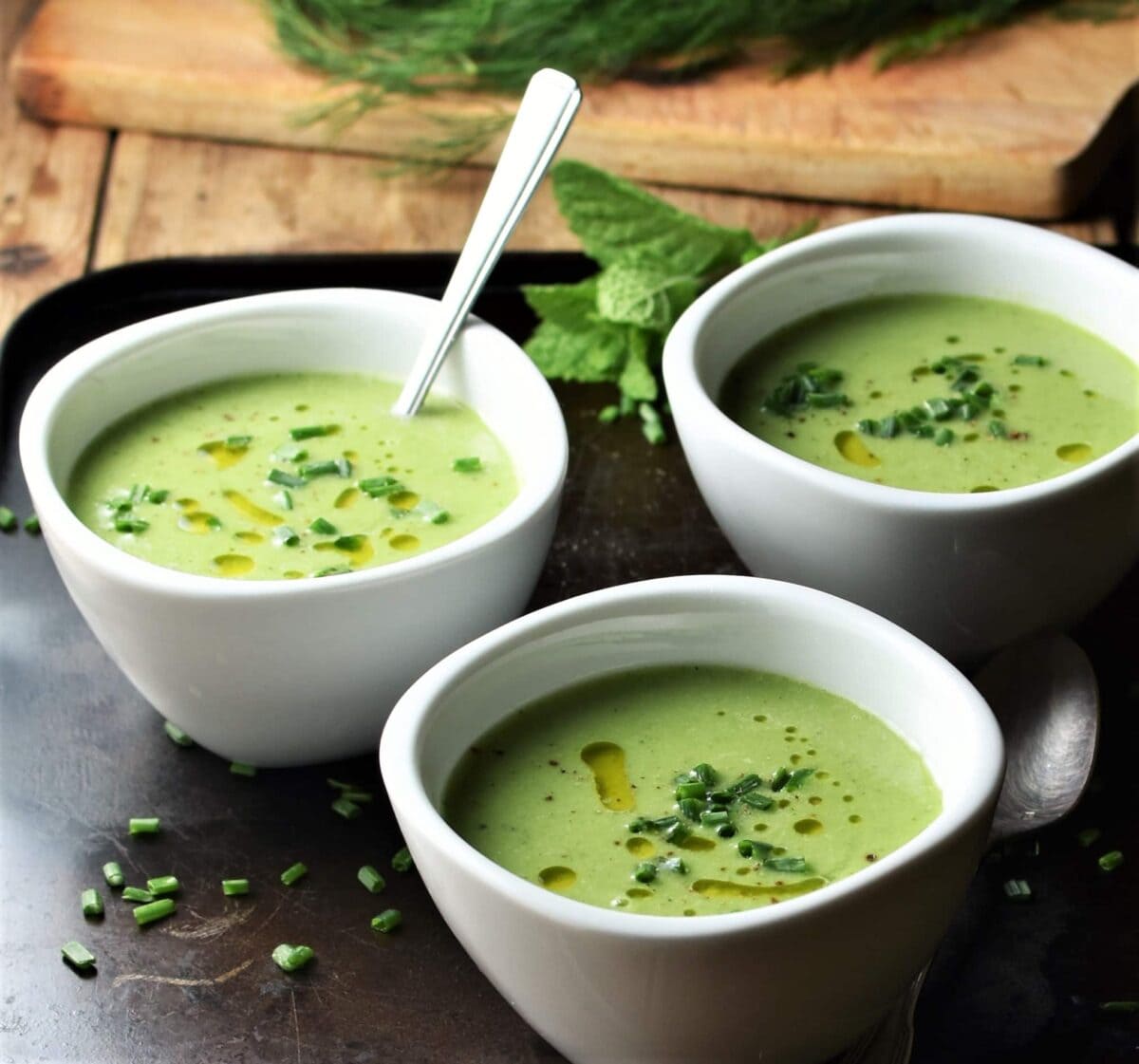 Side view of 3 white bowls with creamy cold cucumber soup.