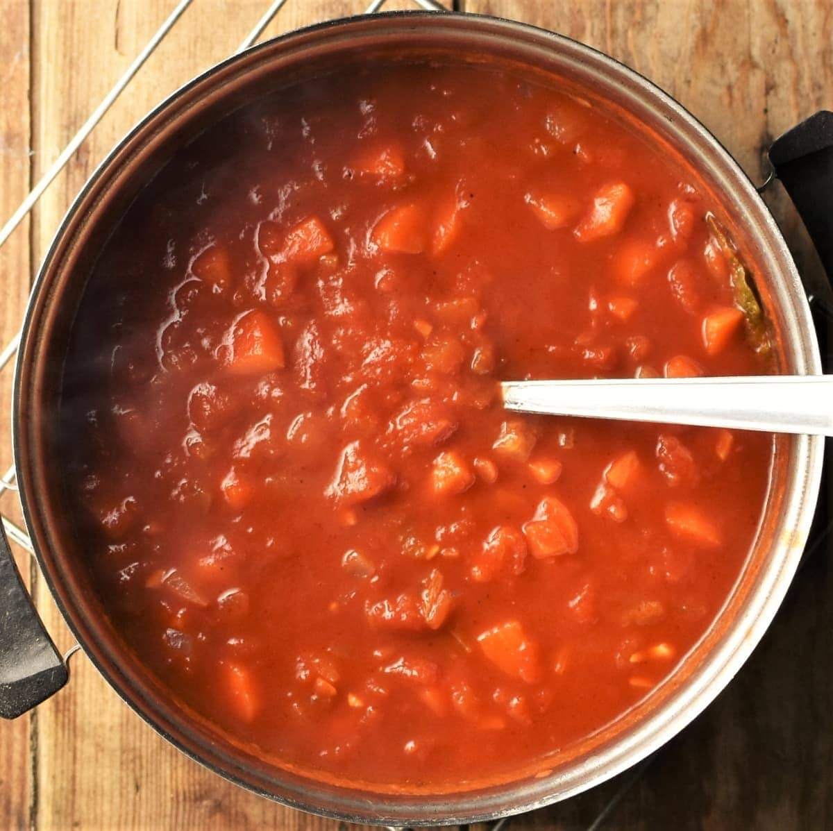 Tomato sauce with vegetables in pot with spoon.