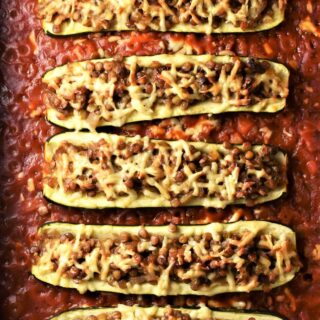 Baked vegetarian lentil stuffed zucchini in tomato sauce.