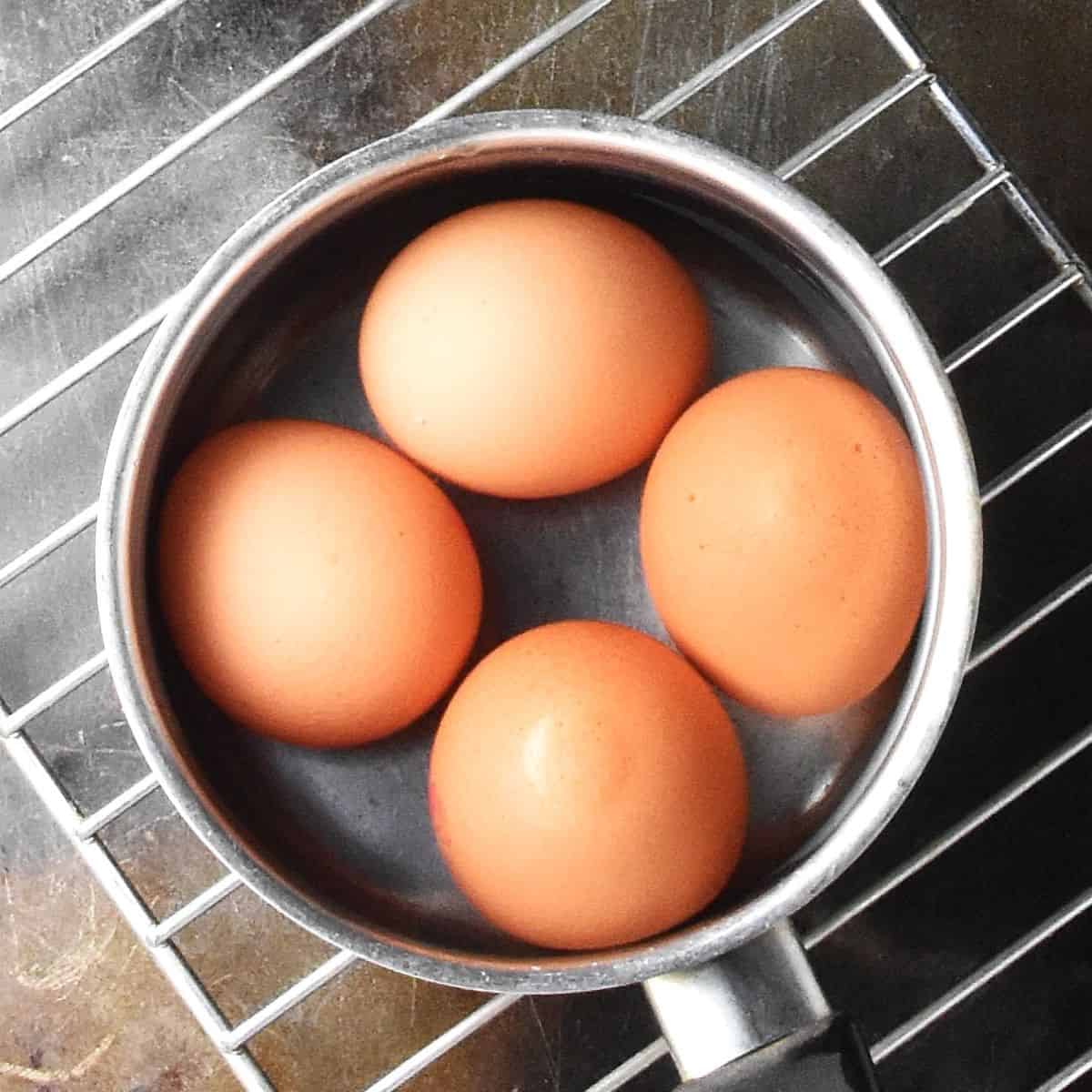 4 eggs in shells in small pot with water.