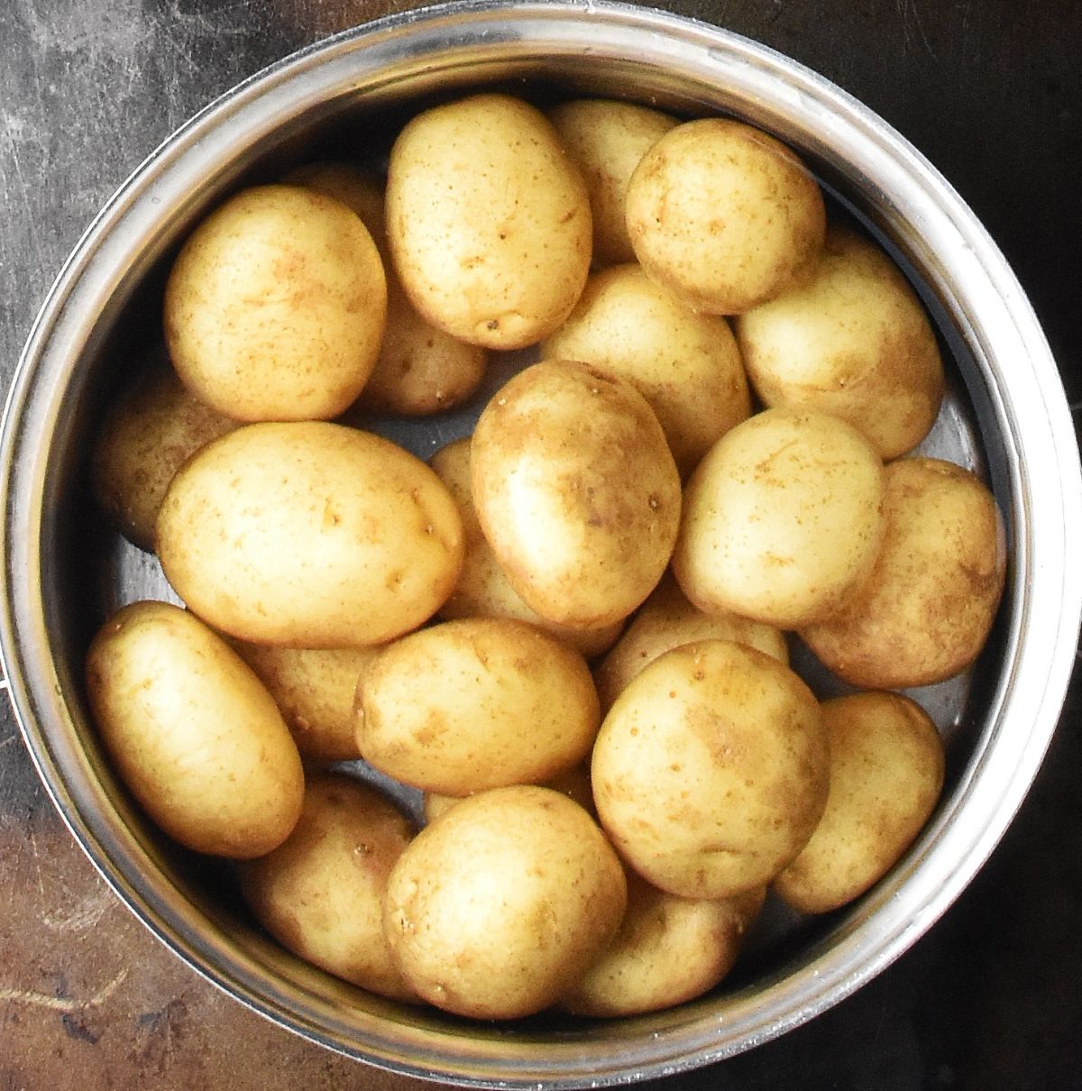 Unpeeled baby potatoes in pot of water.