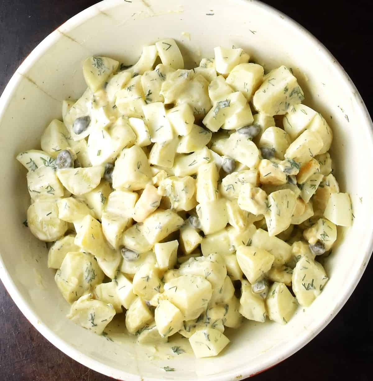 Creamy dill potato egg salad in large white bowl.