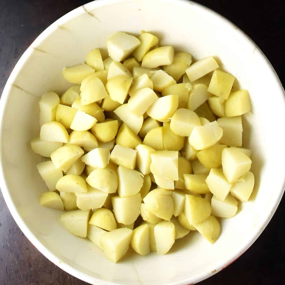 Cubed potatoes in large, white bowl.