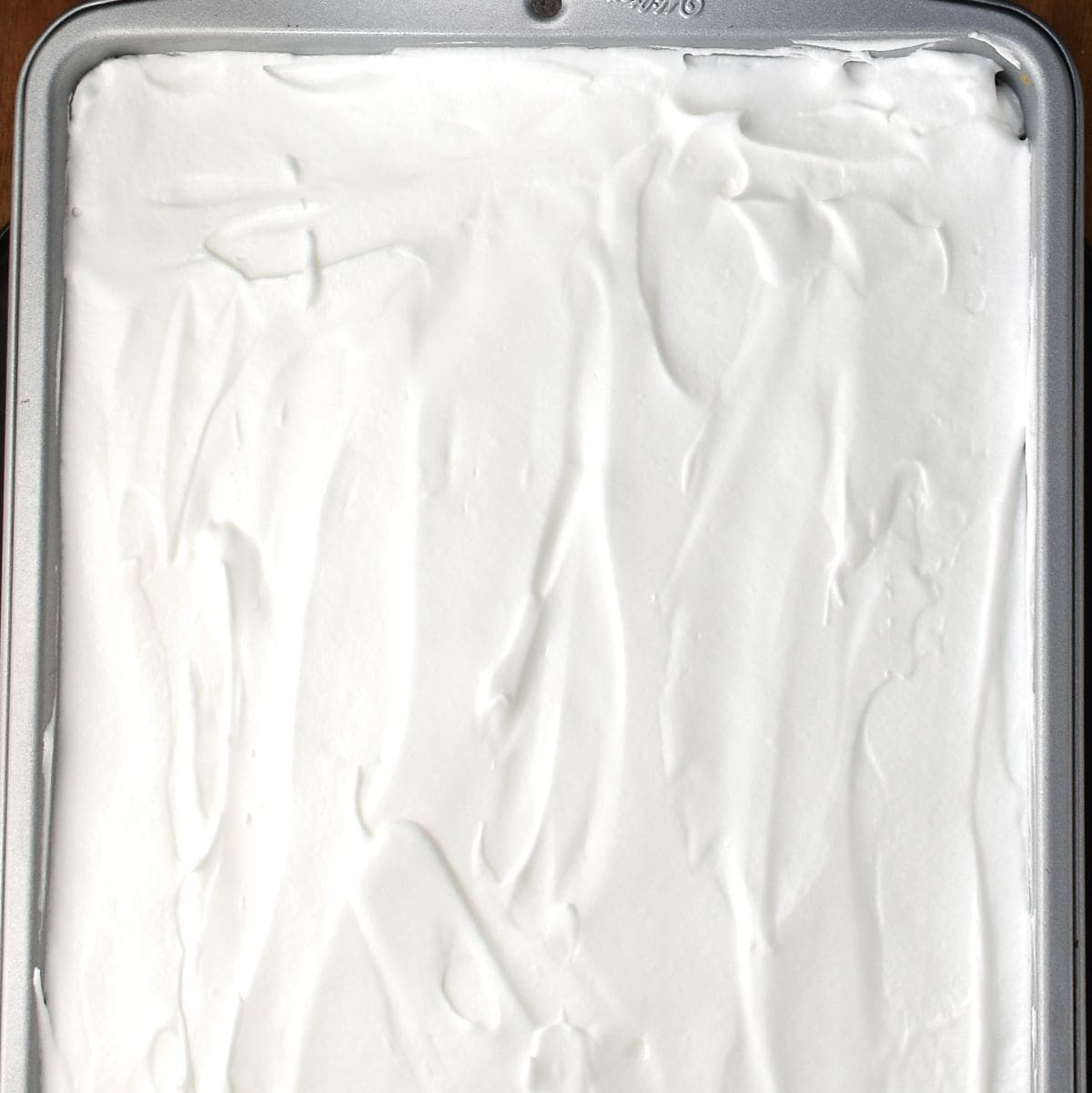 Top down view of meringue layer in plesniak in rectangular cake pan.