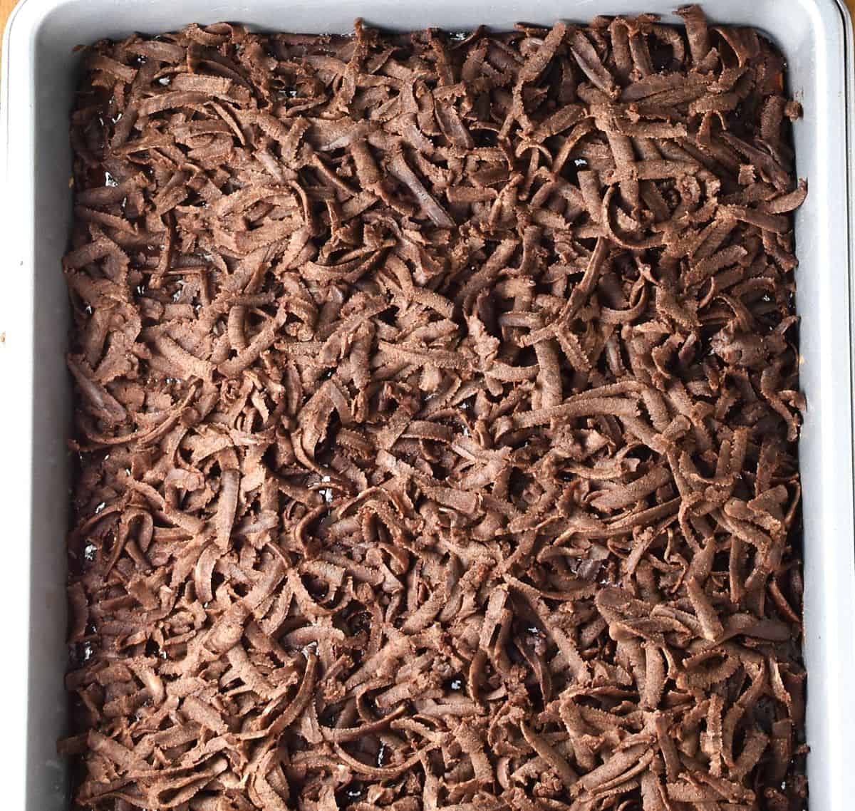 Coarsely grated chocolate dough in rectangular pan.