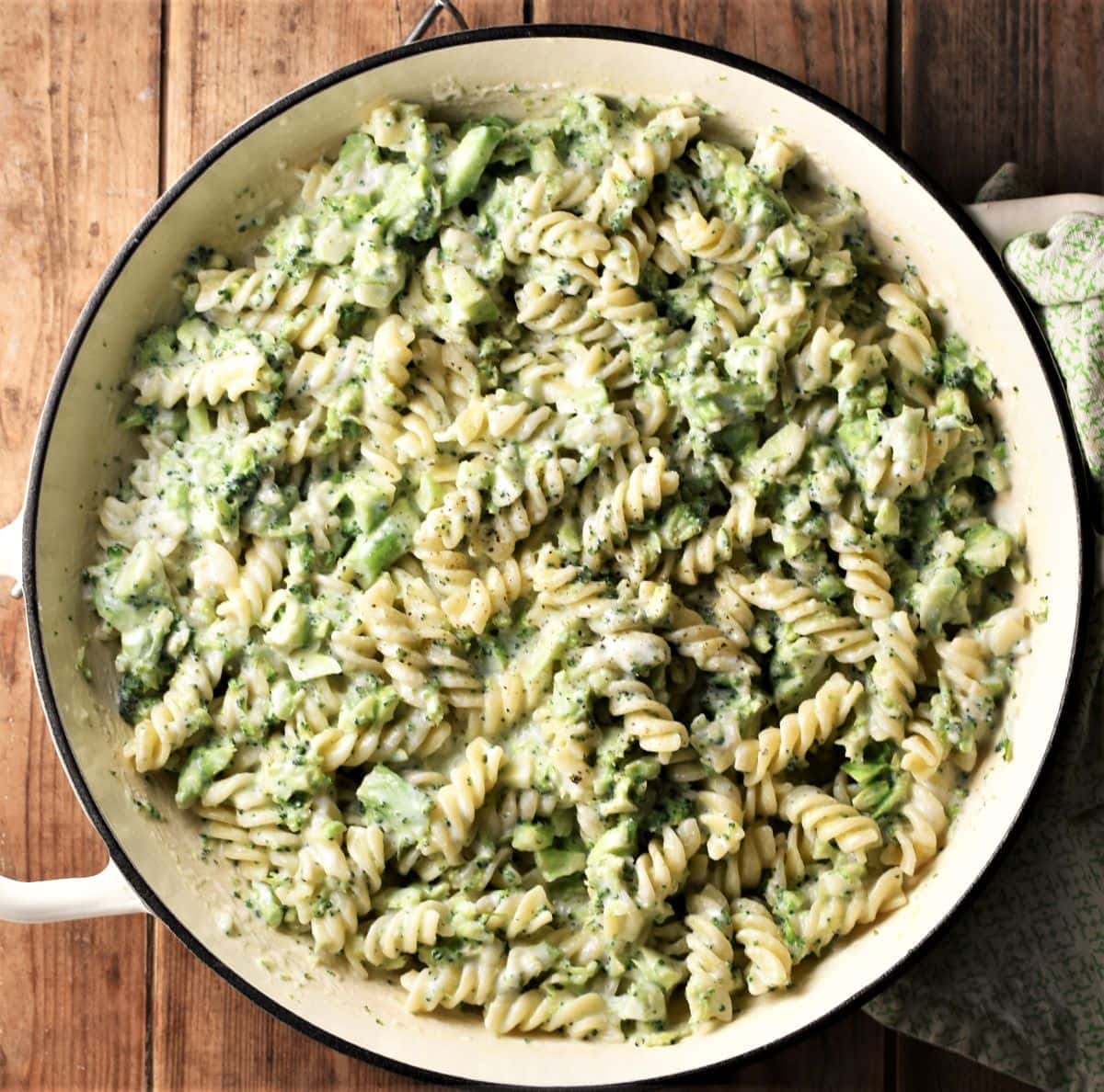 Pasta and broccoli in creamy sauce in large shallow white pan.