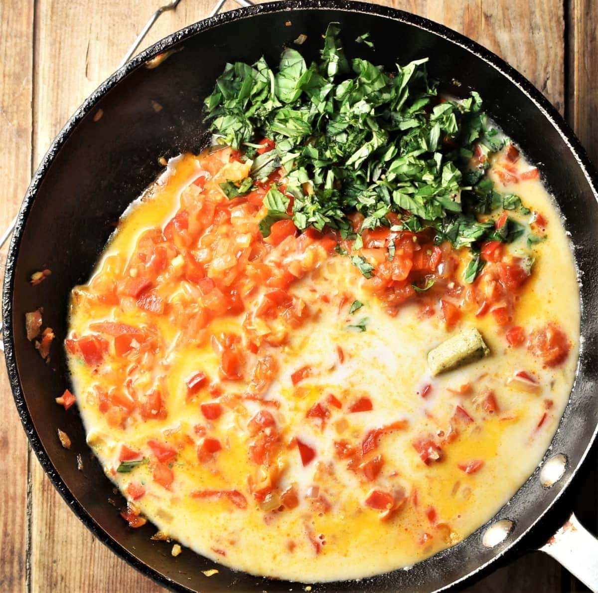 Coconut vegetables sauce with herbs in large pan.