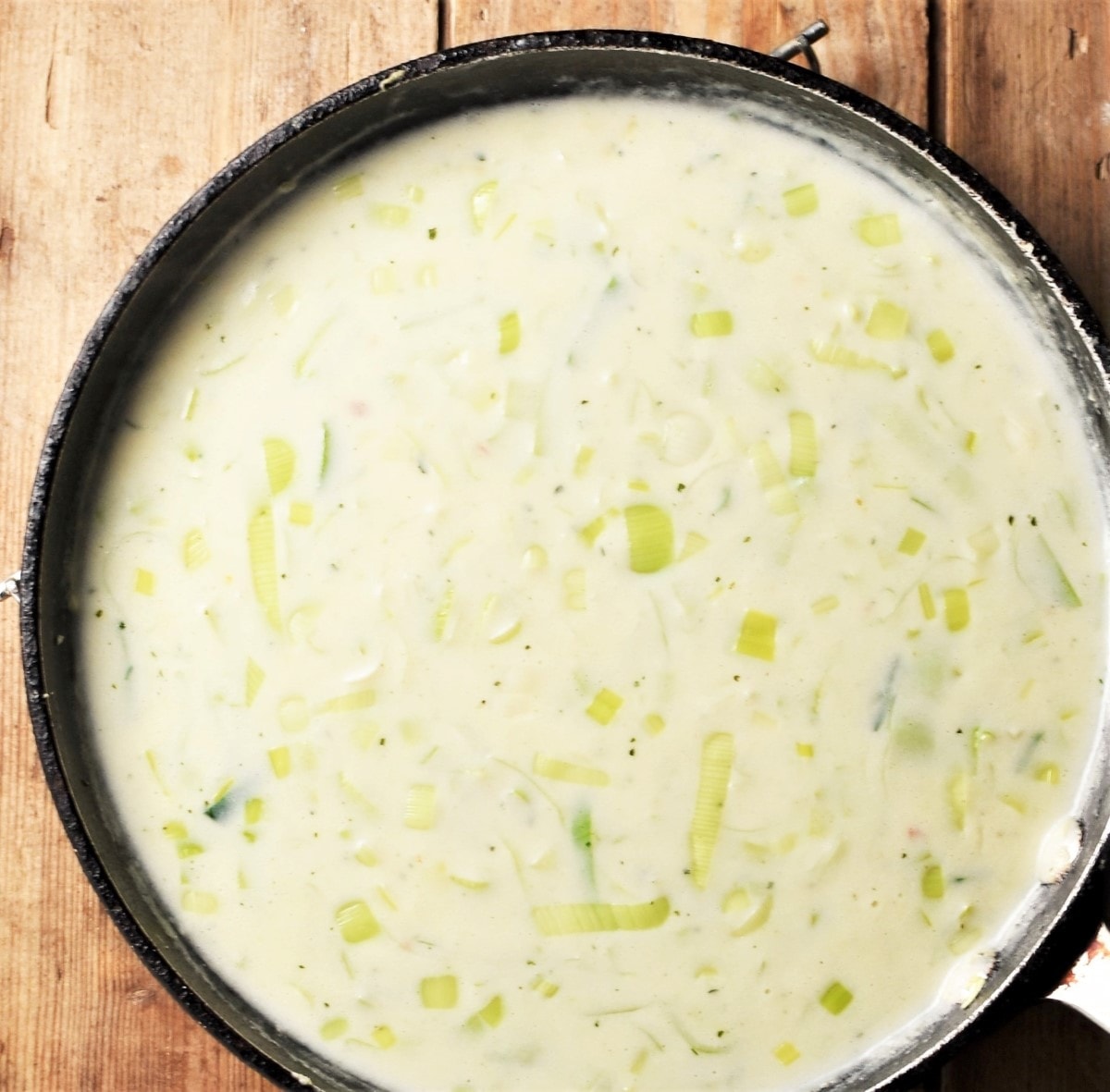 Creamy sauce with leek in large pan.