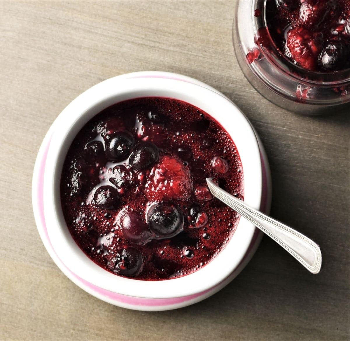 Top down view of fruit compote in white bowl with spoon.