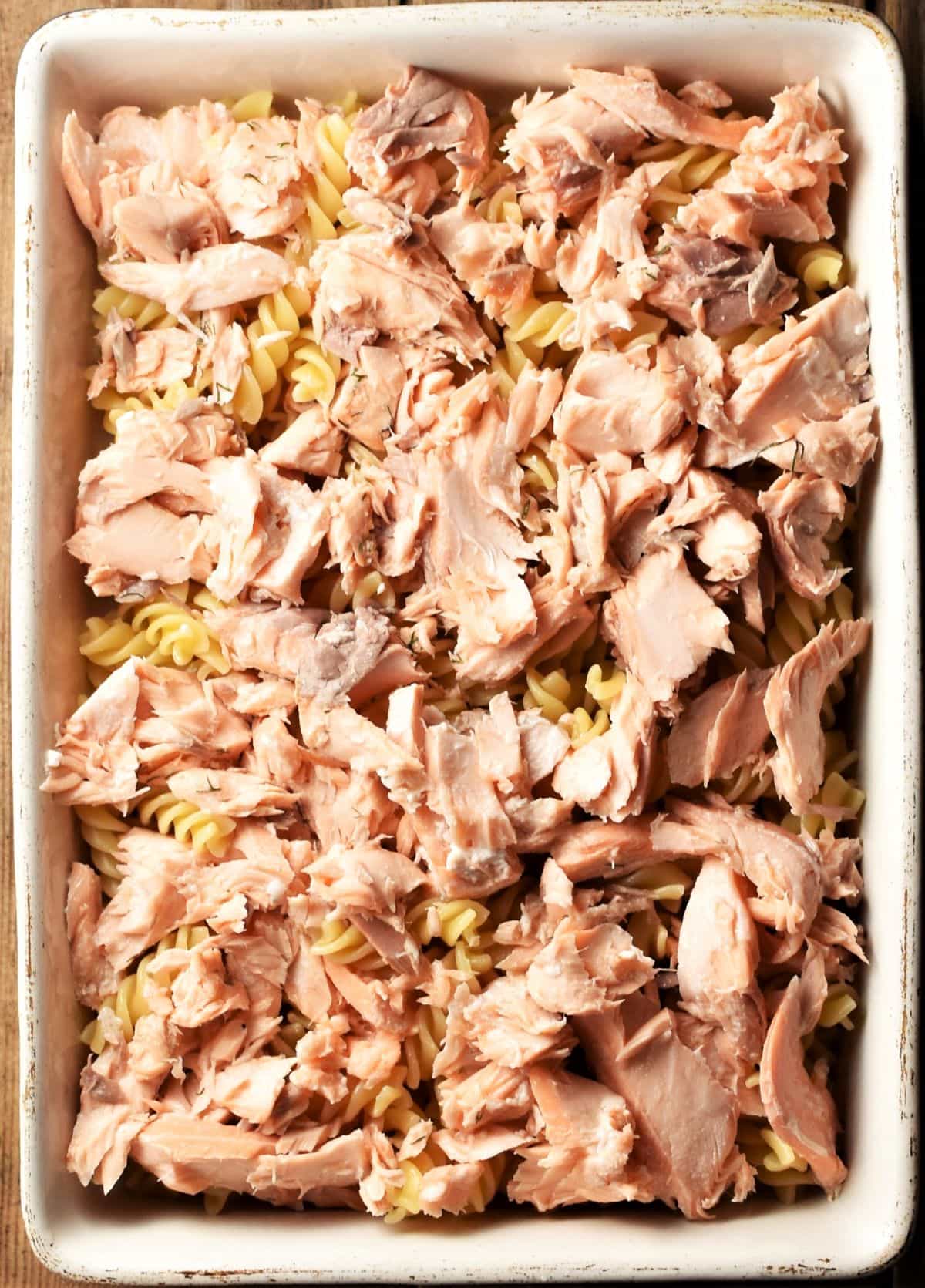 Pasta topped with cooked salmon in casserole dish.