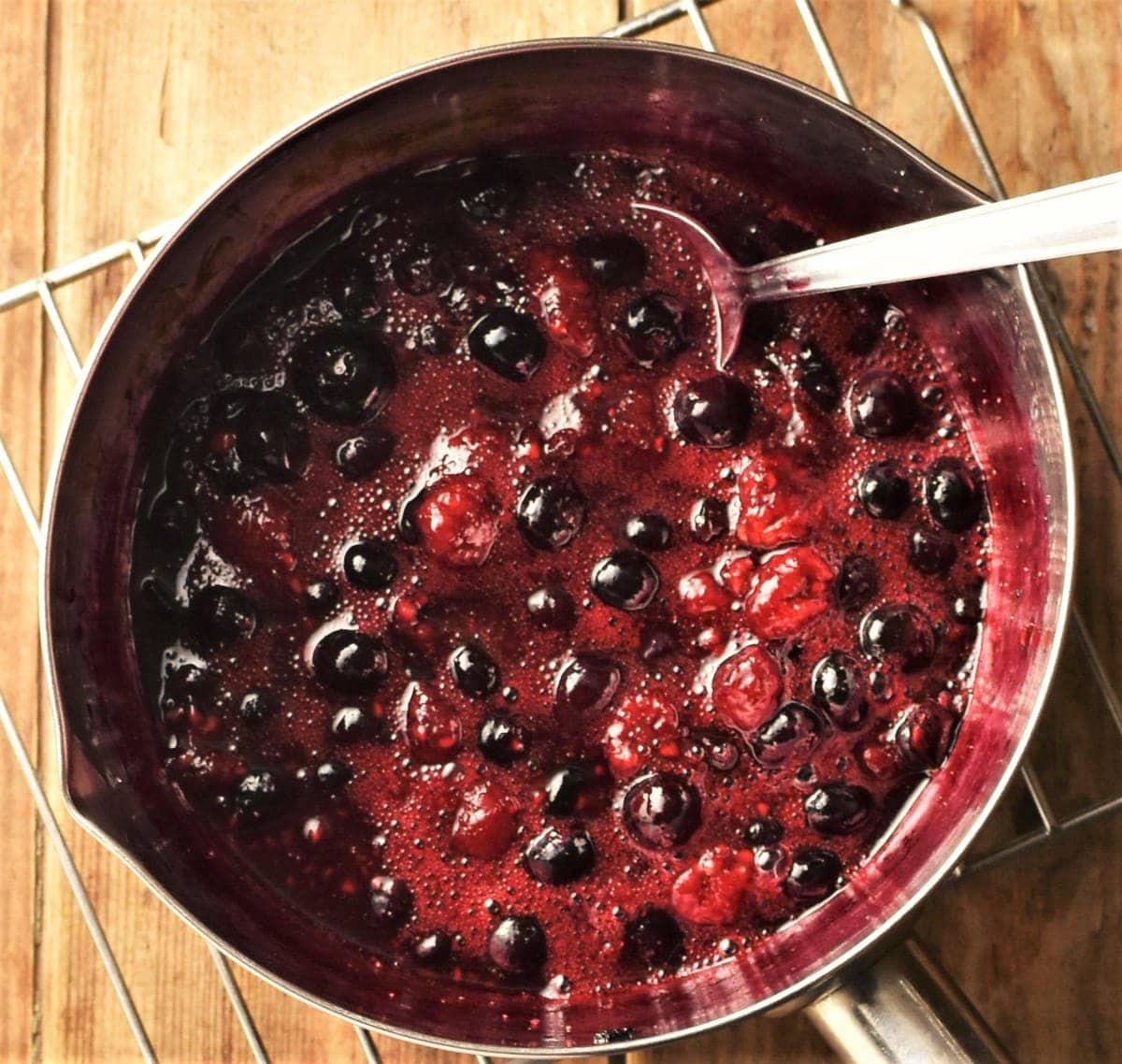 Fruit compote in saucepan with spoon.
