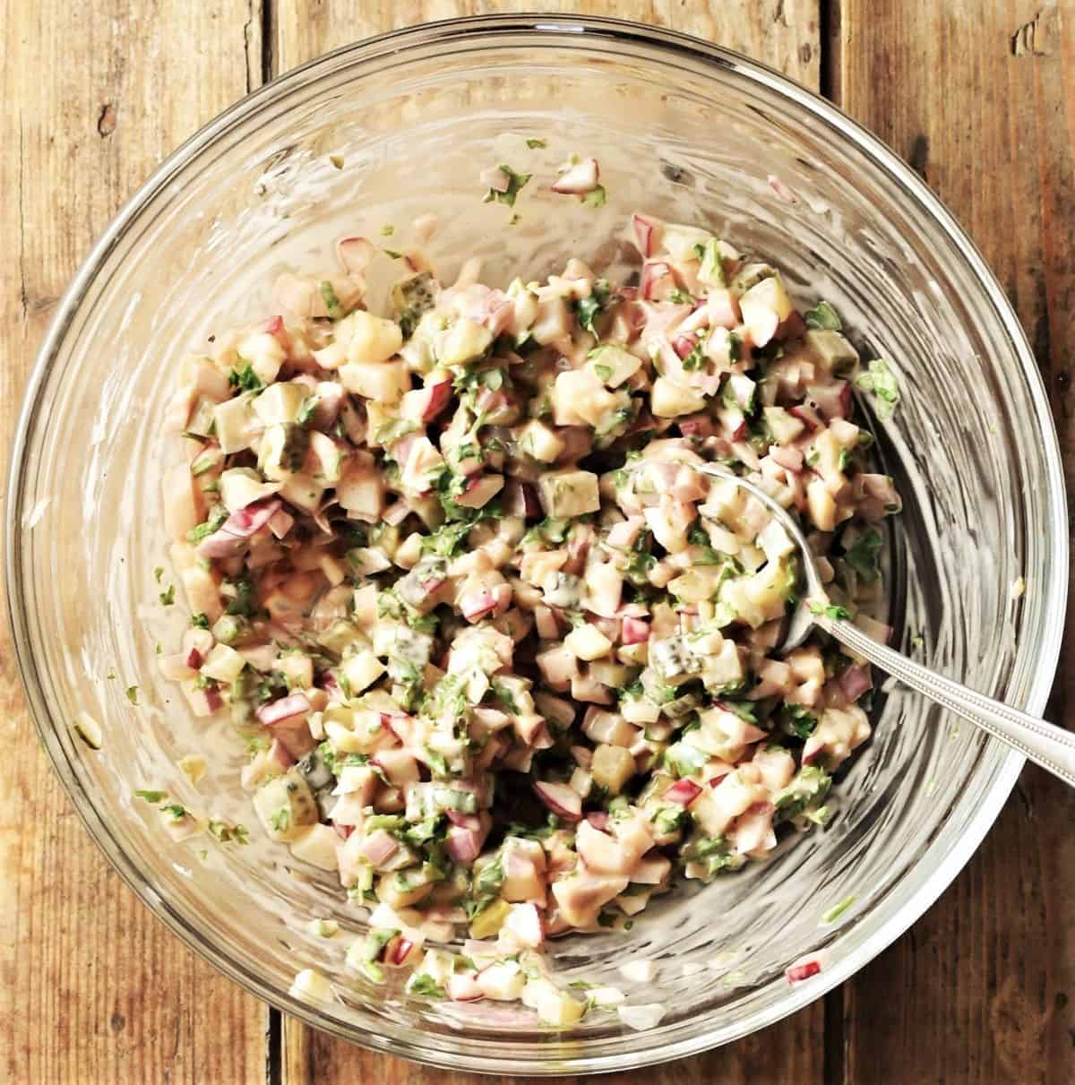 Top down view of sardines mixture in glass bowl with spoon.