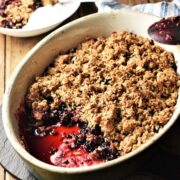 Side view of blackberry crumble in white oval dish.