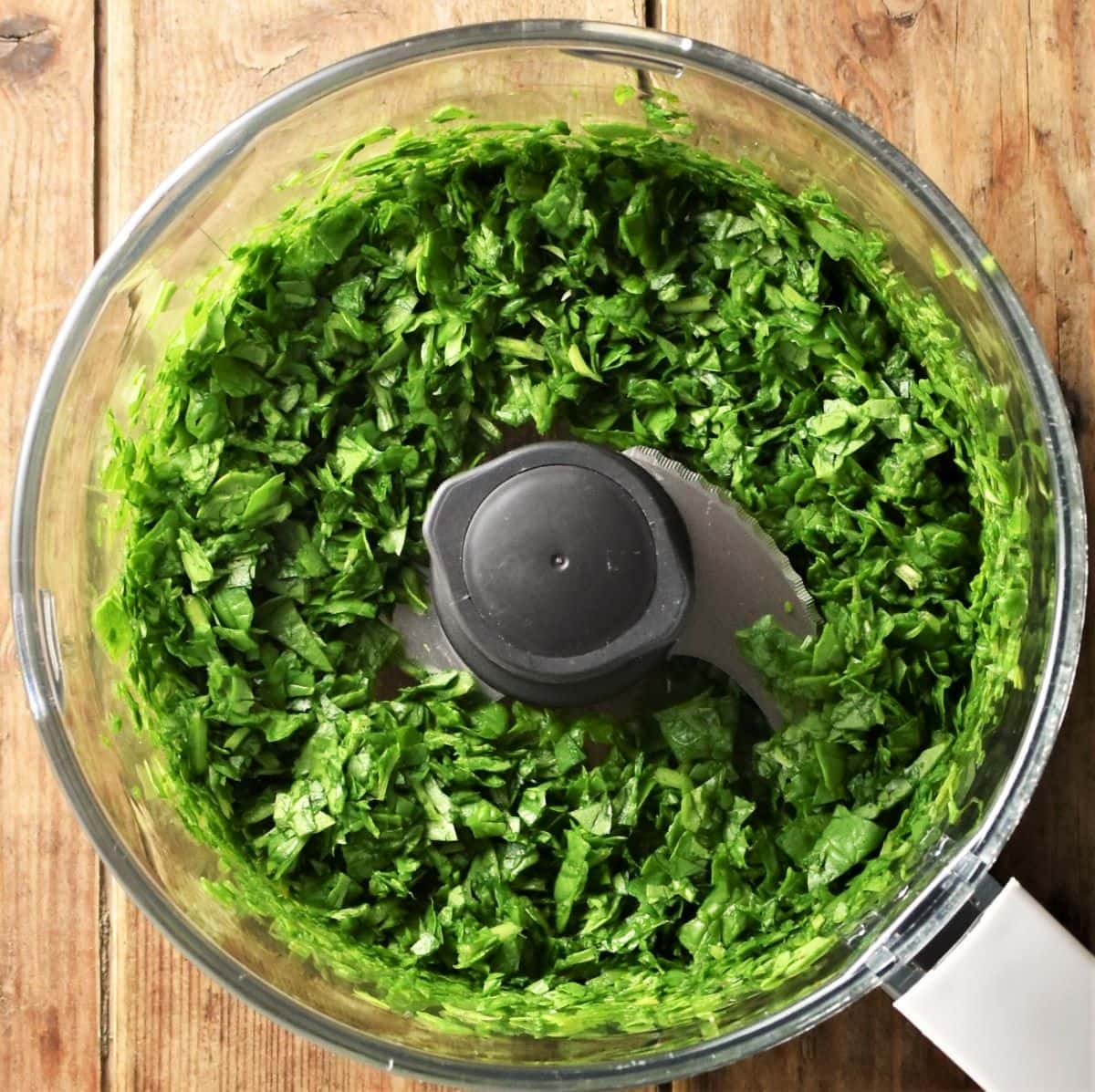 Finely chopped fresh spinach in food processor bowl.