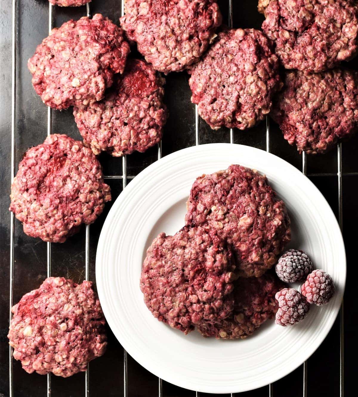Raspberry cookies on top of white plate and rack.