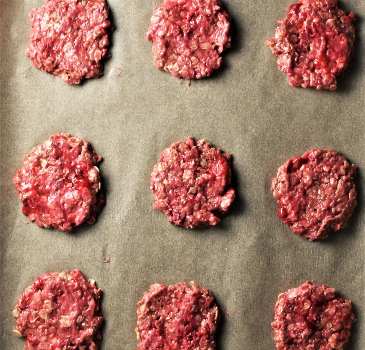Unbaked raspberry cookies on top of parchment.
