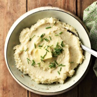 Top down view of celery root puree in green bowl with spoon.