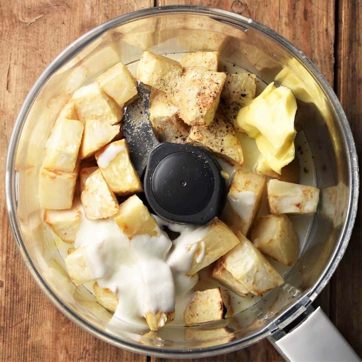 Cubed celeriac and yogurt in food processor bowl.