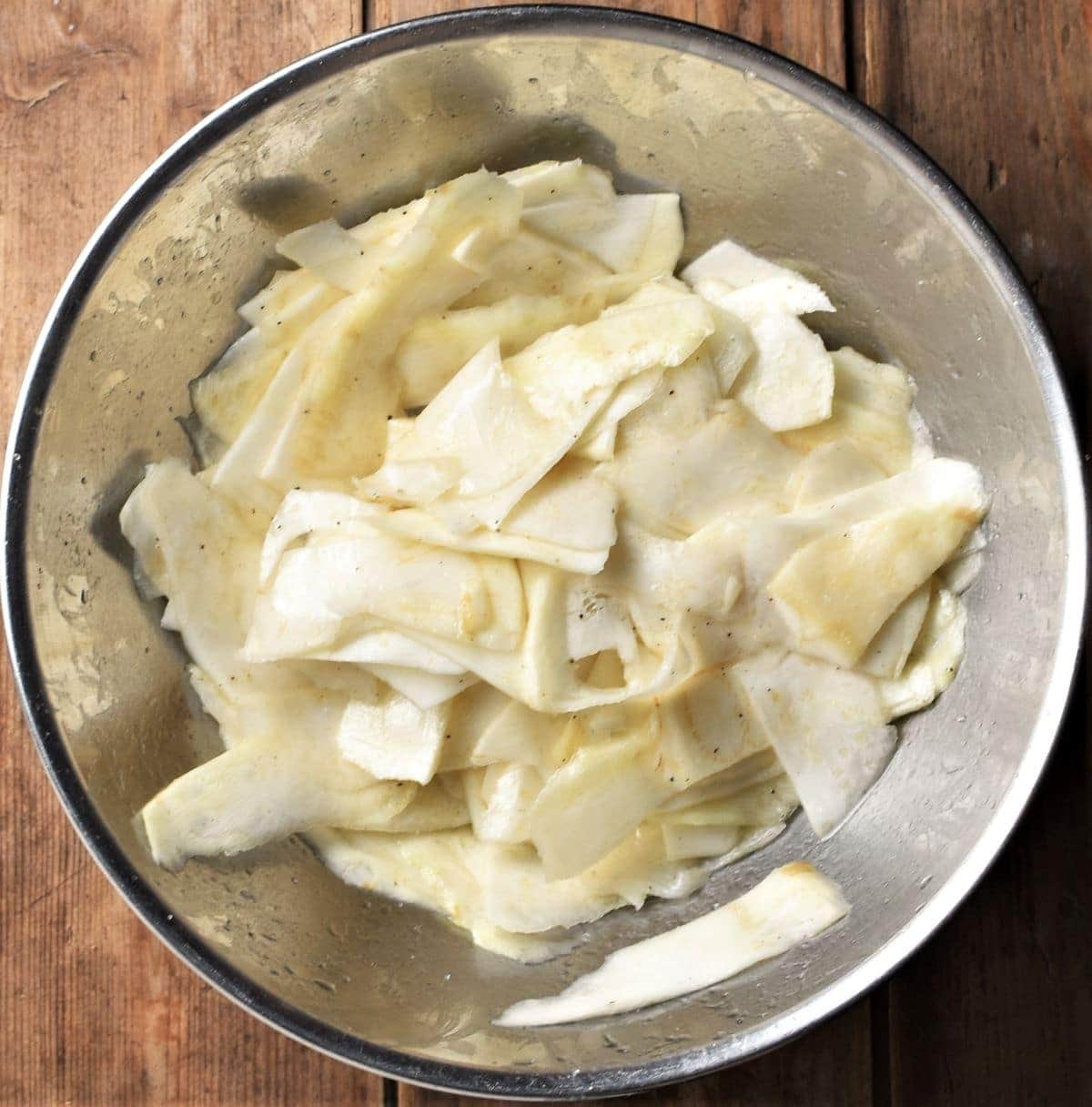 Celeriac shavings in large metal bowl.
