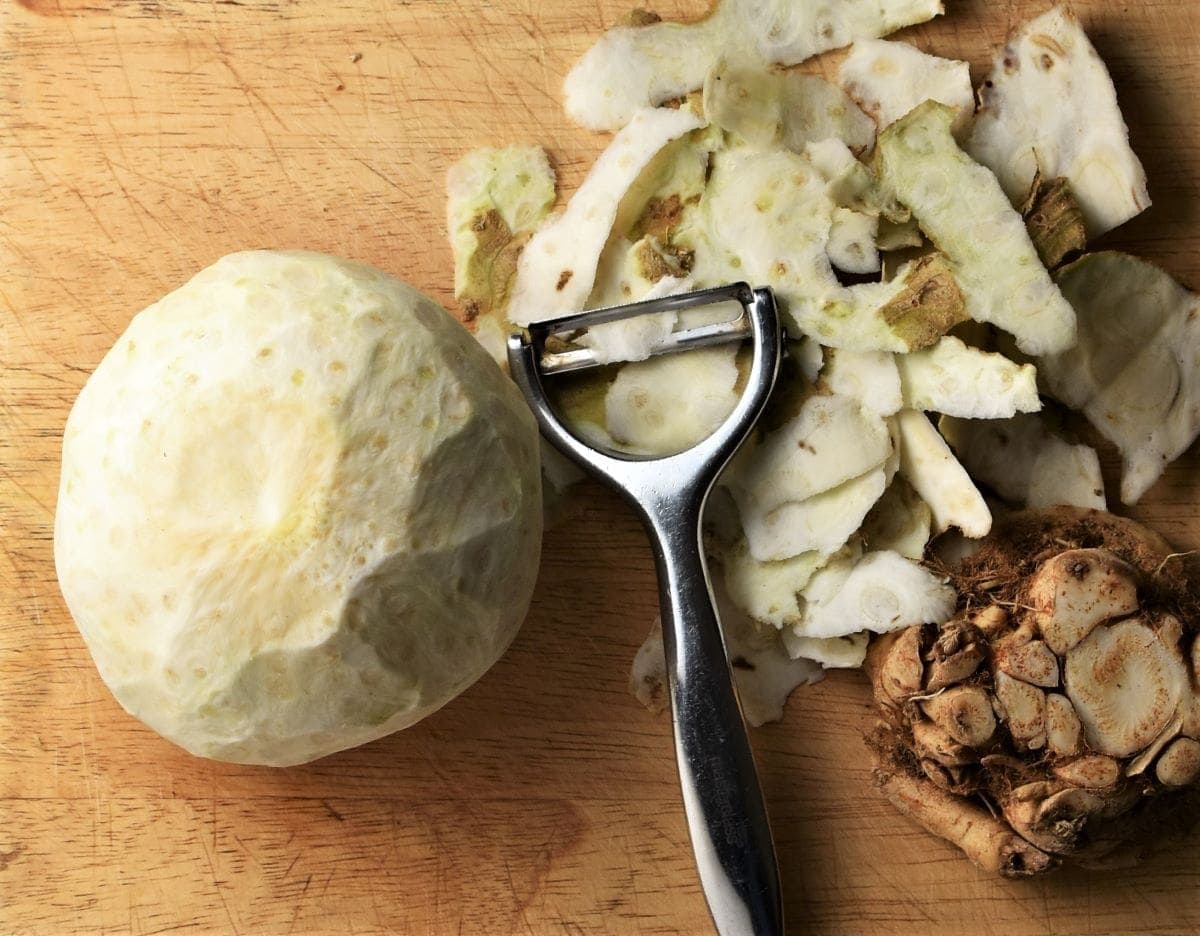 Peeled whole celeriac with vegetable peeler and peel.