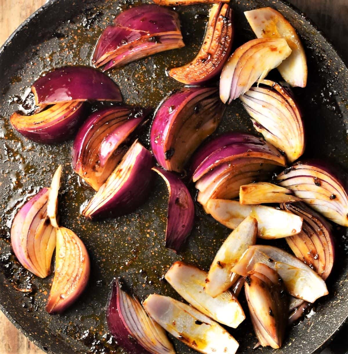 Red onion wedges with balsamic dressing in large pan.
