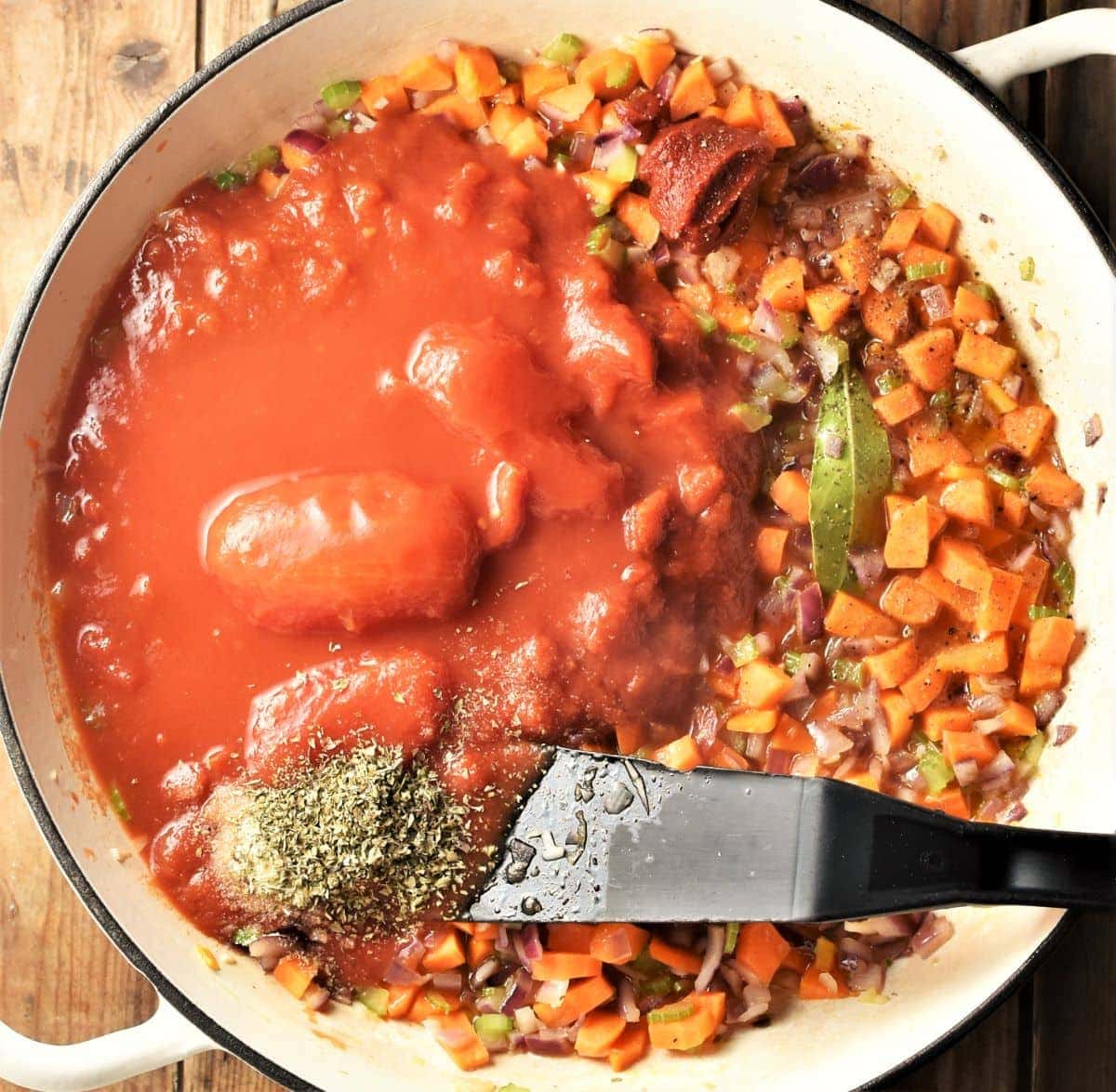 Making bolognese sauce in large white pan with black spatula.
