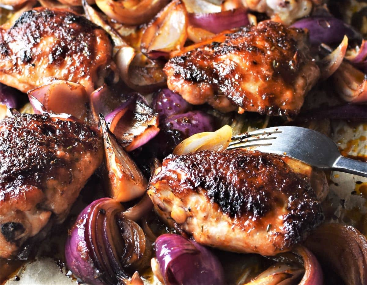 Close-up view of roasted chicken pieces with onions.