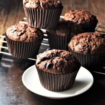 Side view of chocolate sweet potato muffins on plate and rack.