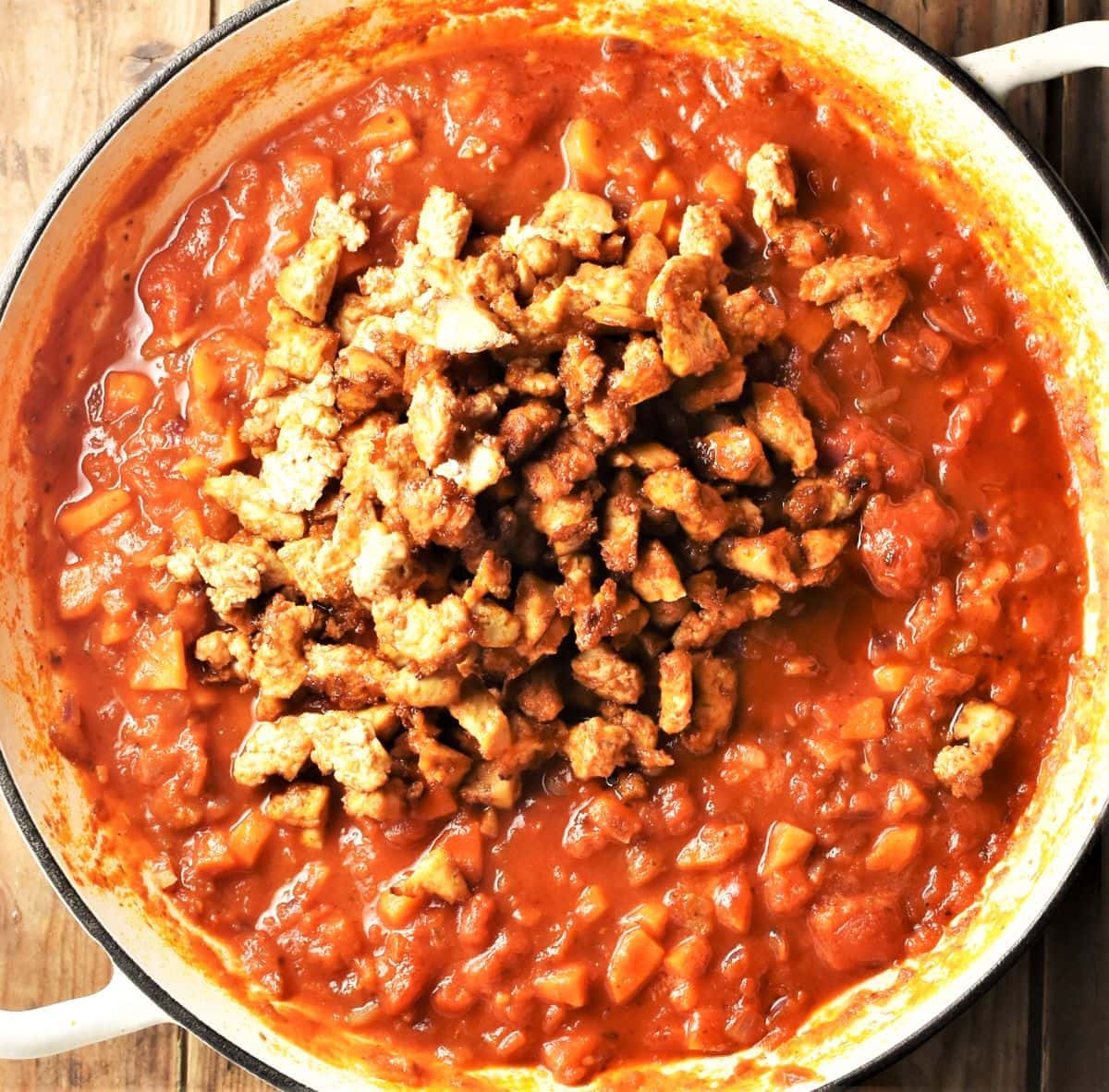 Tomato sauce with baked tofu crumbs in large white pan.