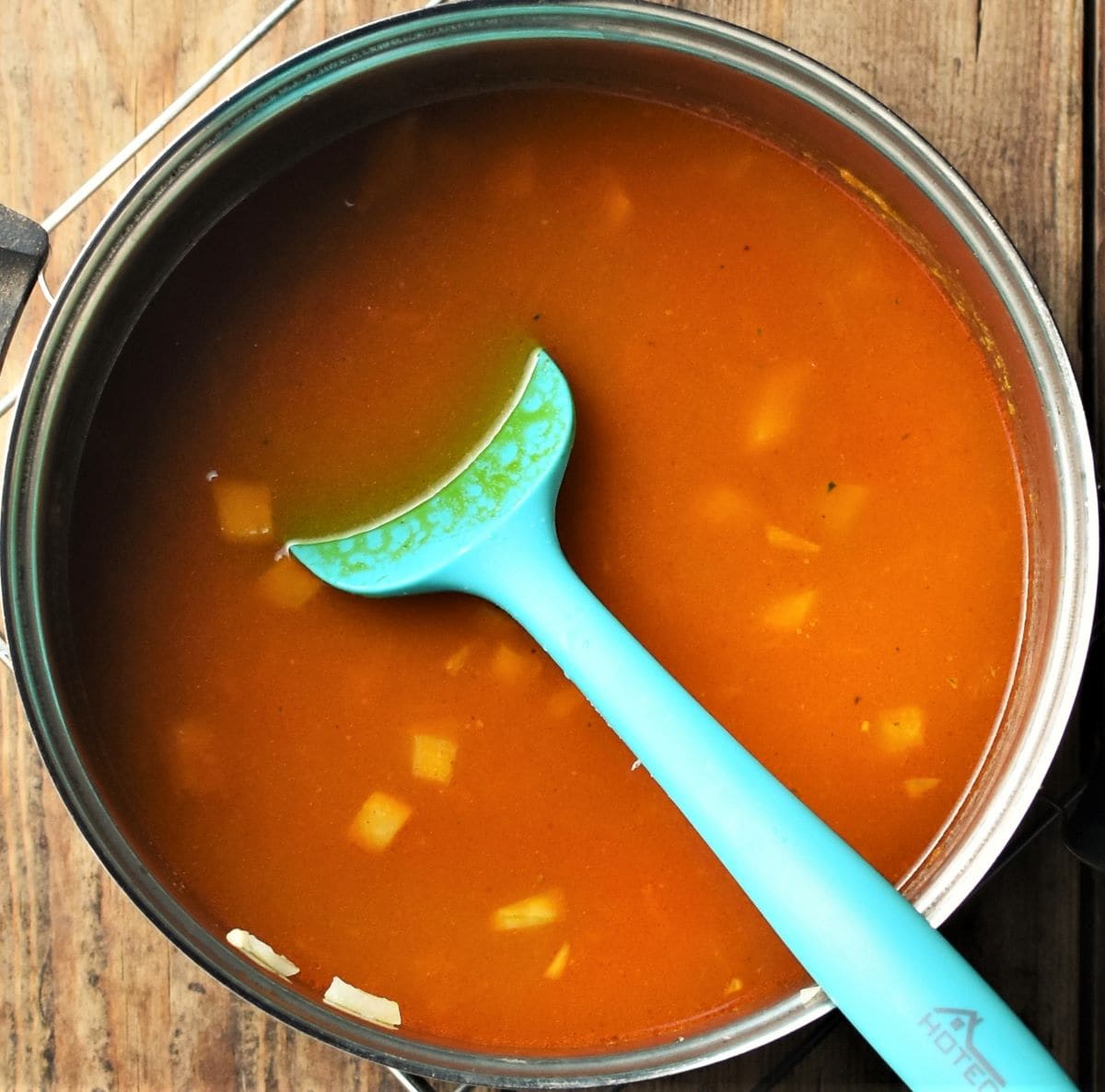 Cooking dhal in saucepan with green spoon.