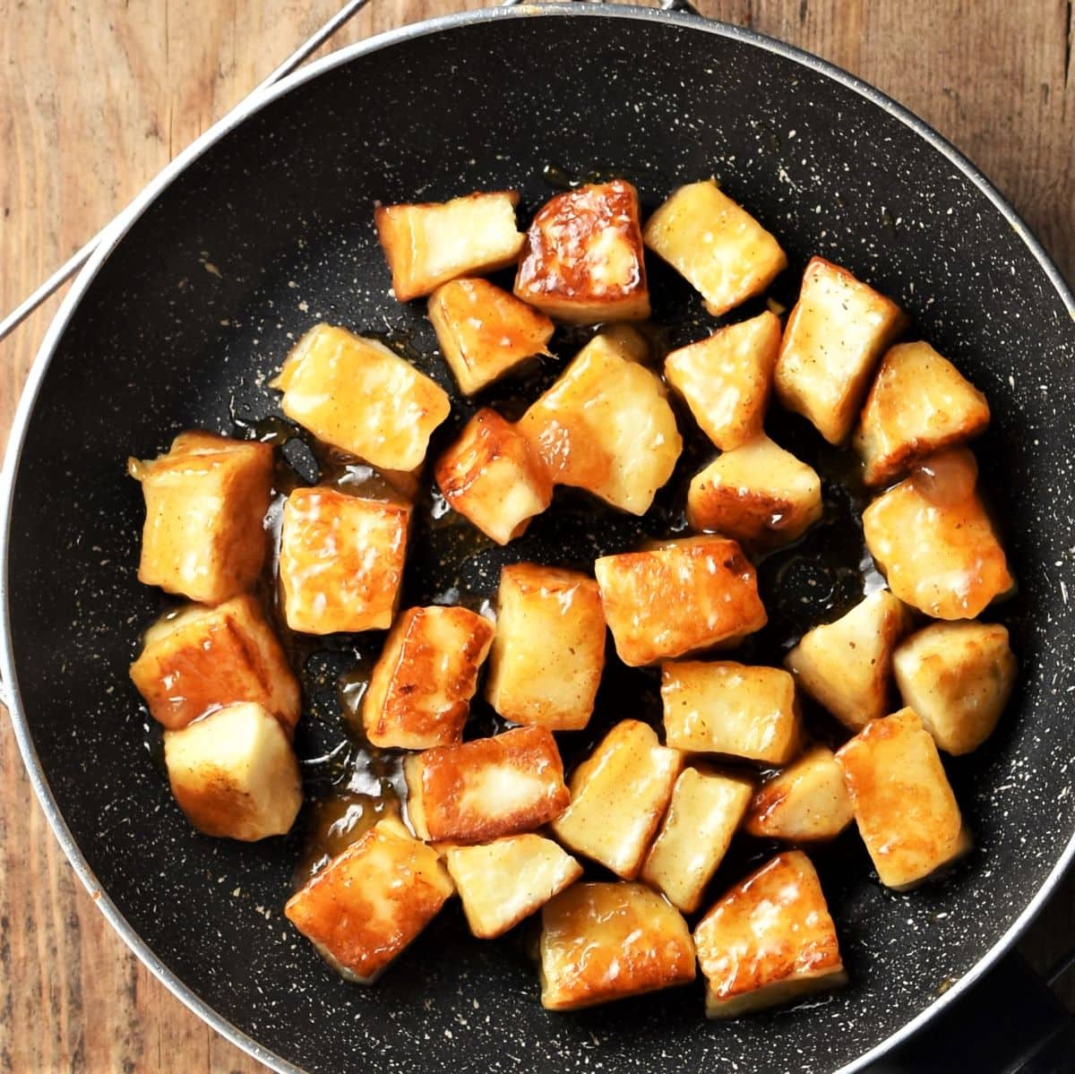Cubed fried halloumi coated in chutney in pan.