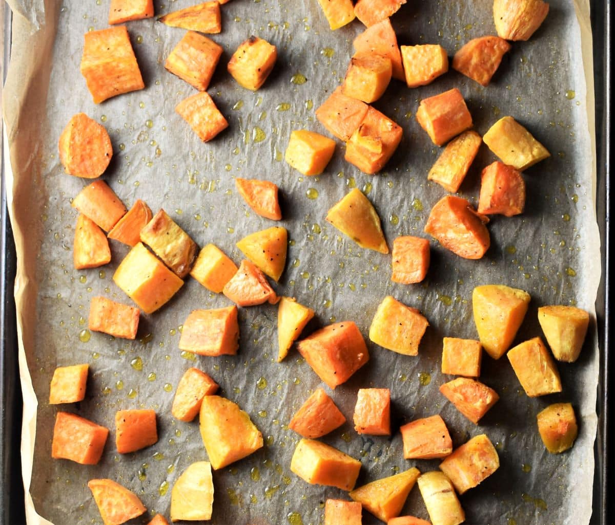 Cubed roasted sweet potato on top of tray lined with parchment.