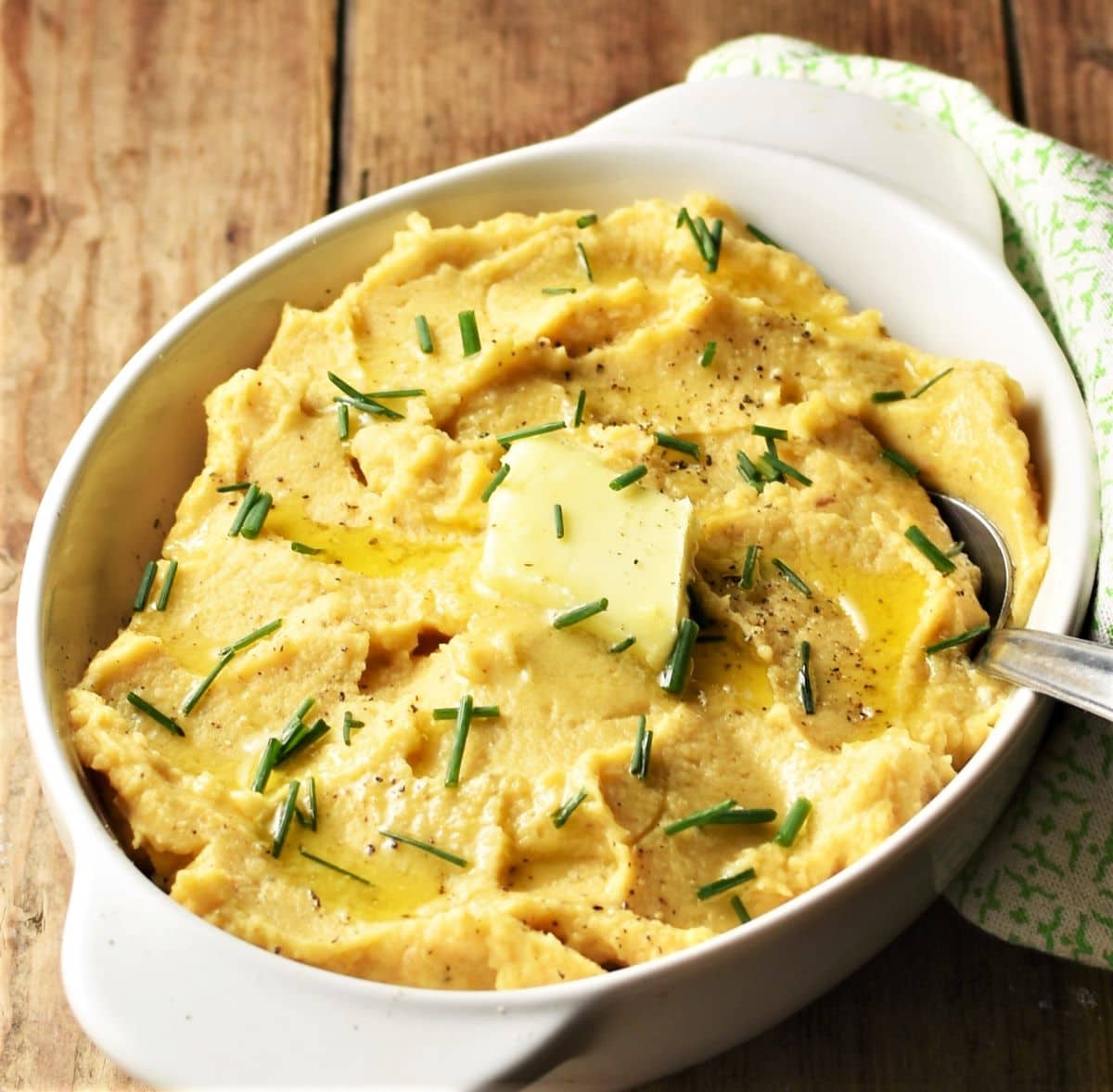 Close-up side view of swede mash garnished with chives in white dish.