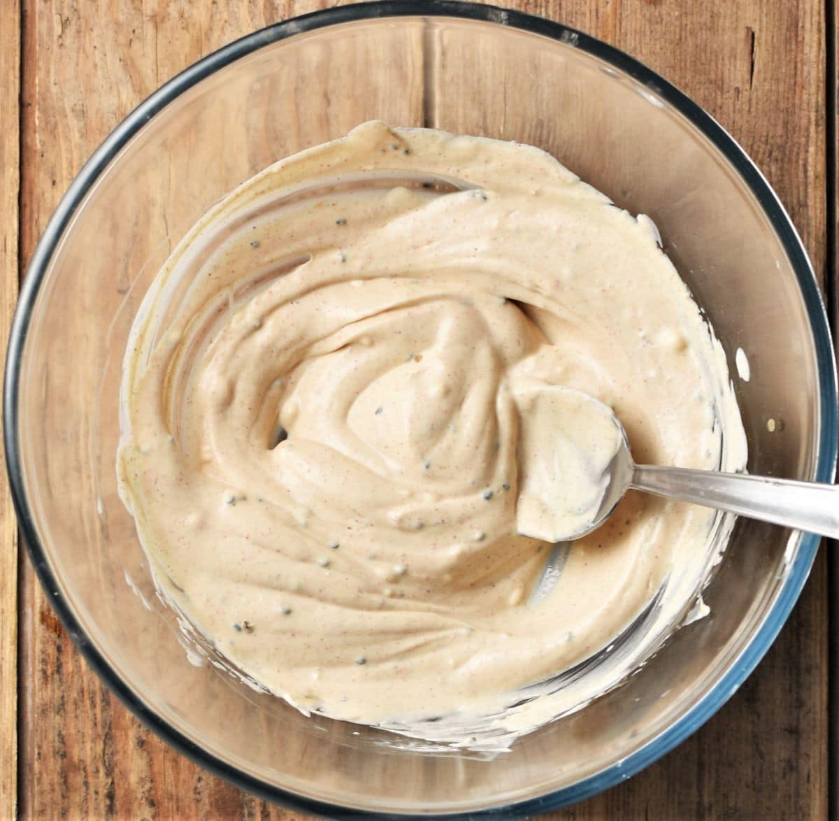 Creamy dressing in mixing bowl with spoon.