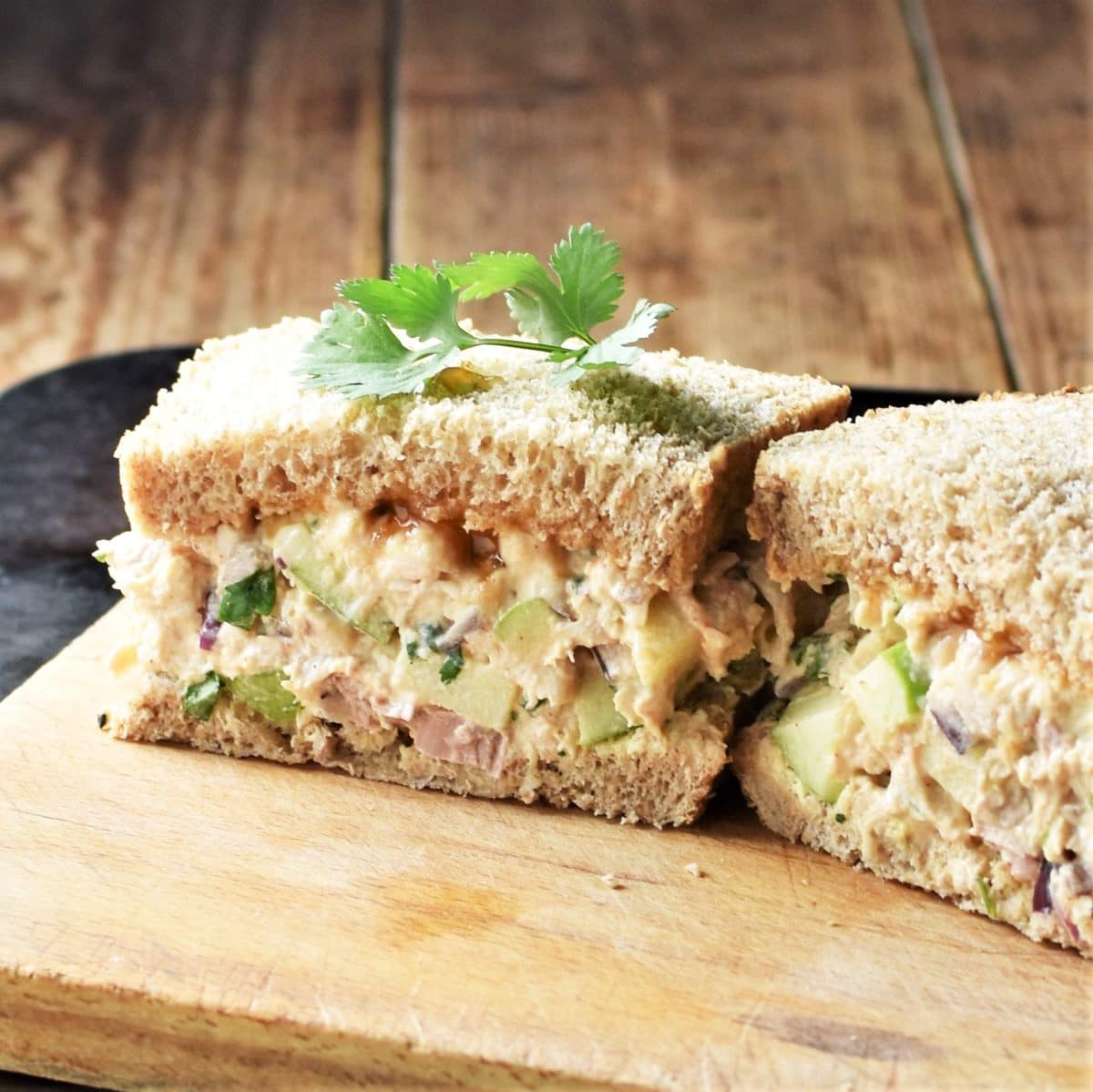 Side view of turkey salad sandwich on top of cutting board.