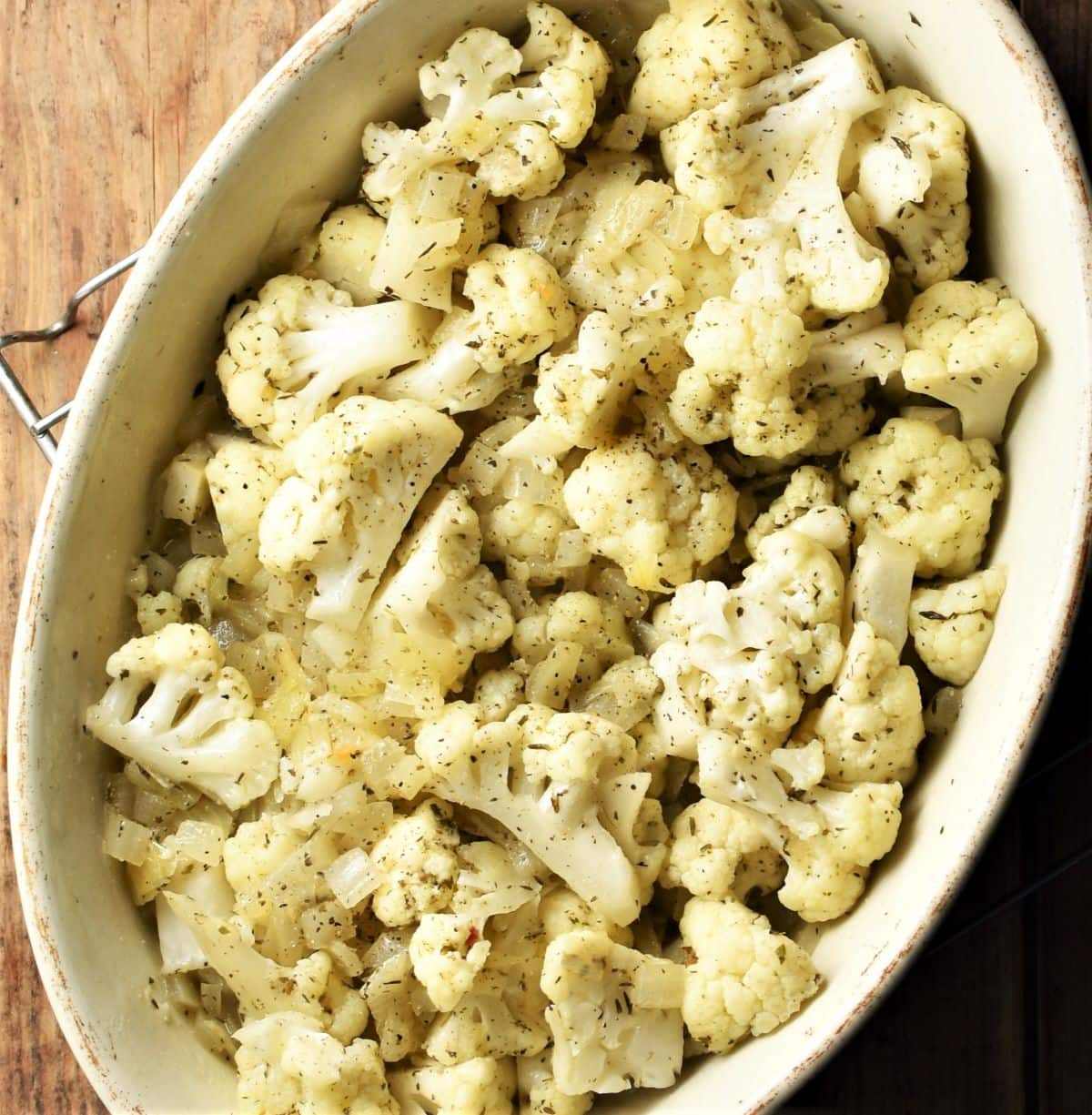 Cauliflower, onion and herb mixture in white oval dish.