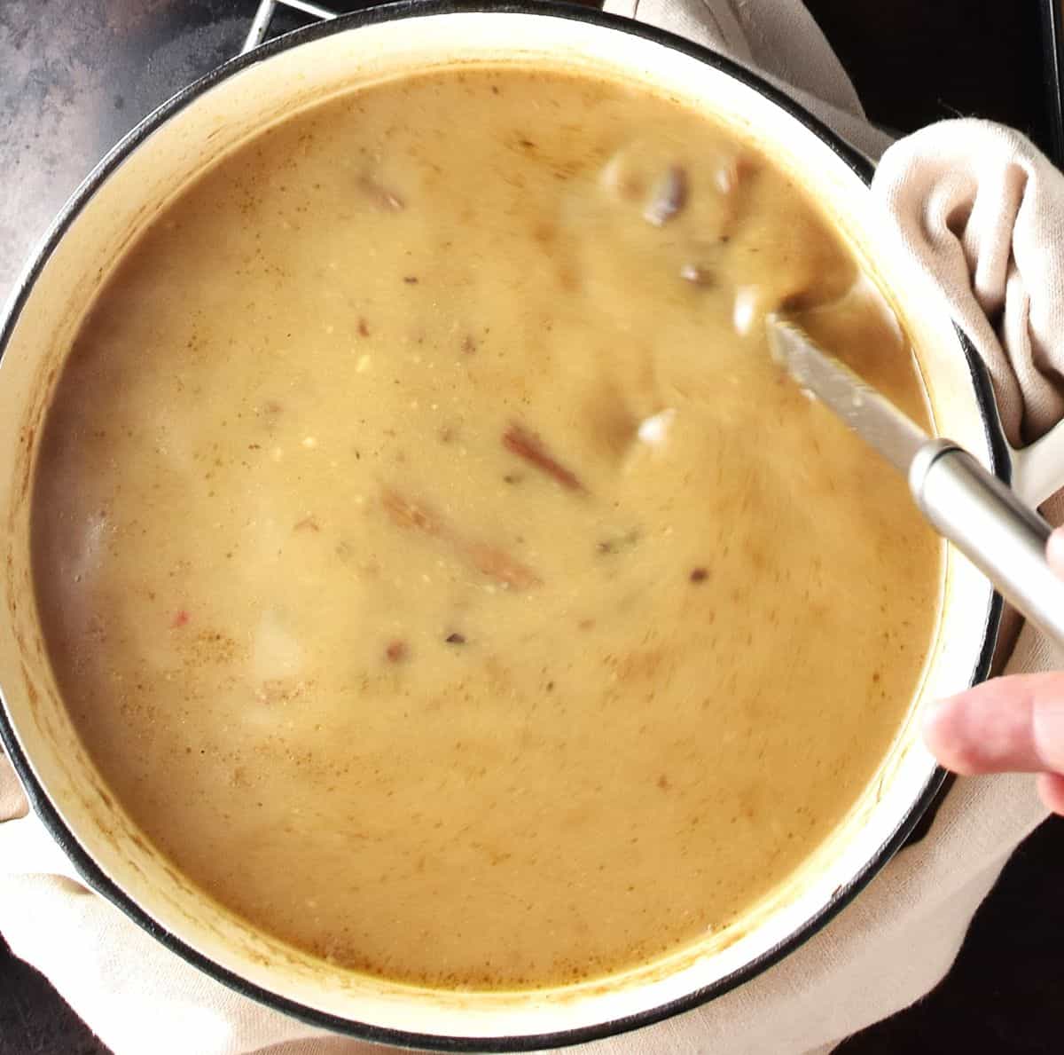 Top down view of creamy Polish Christmas mushroom soup in white pot with ladle.