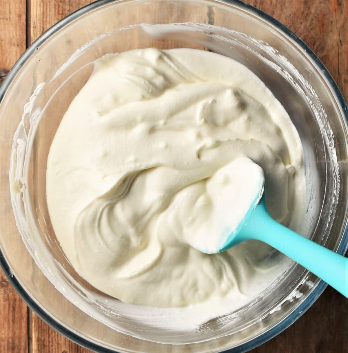 Creamy tiramisu mixture in bowl with blue spoon.