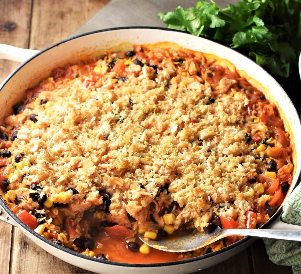 Side view of leftover turkey casserole in large white pan with spoon.