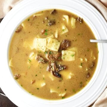 Top down view of Polish Christmas mushroom soup with pasta in white bowl with spoon.