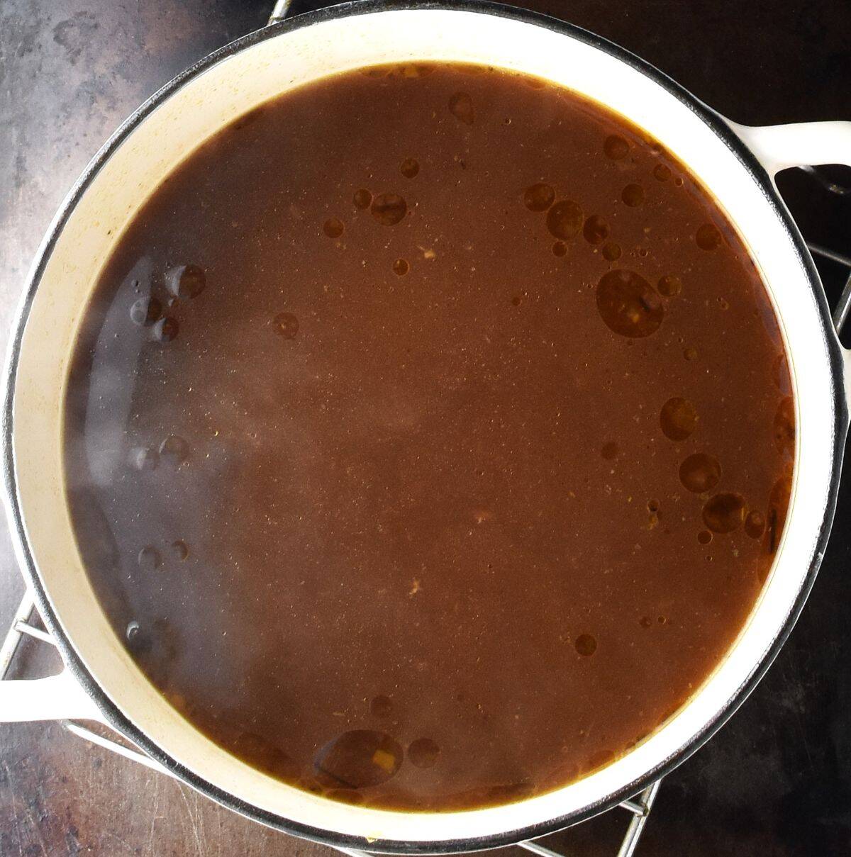 Top down view of brown coloured Polish Christmas Eve wild mushroom soup in white pot.