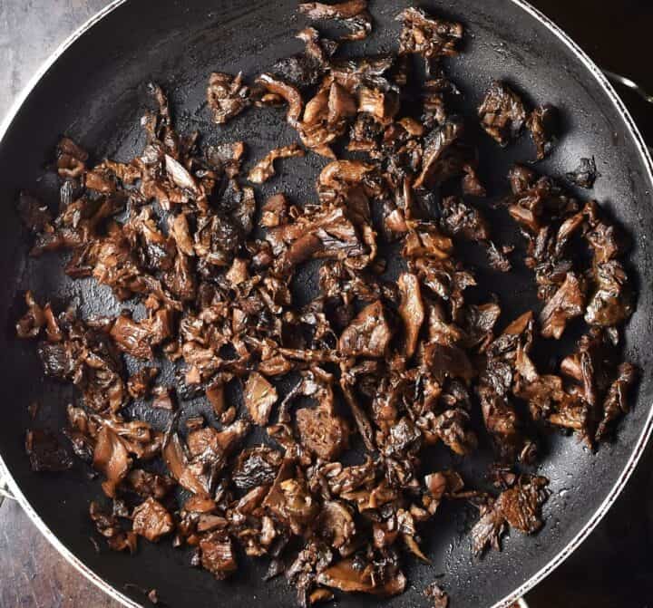 Top down view of chopped wild mushrooms in large pan.