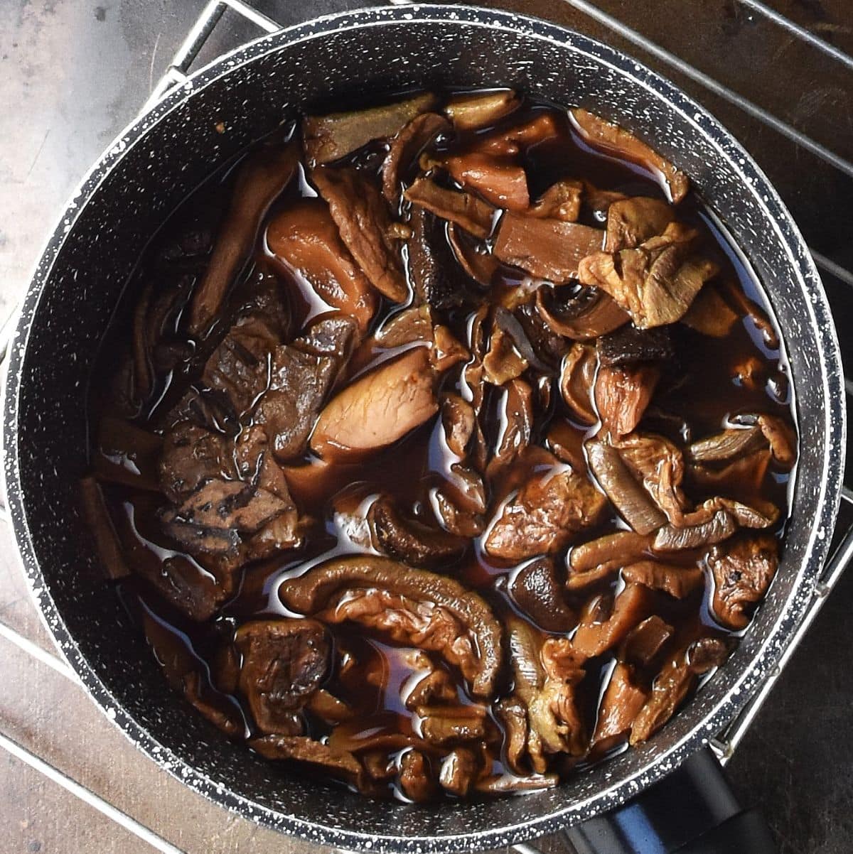 Top down view of wild mushrooms in pot with water.