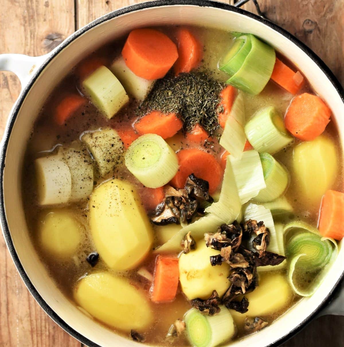 Potatoes and vegetables with stock in pot.