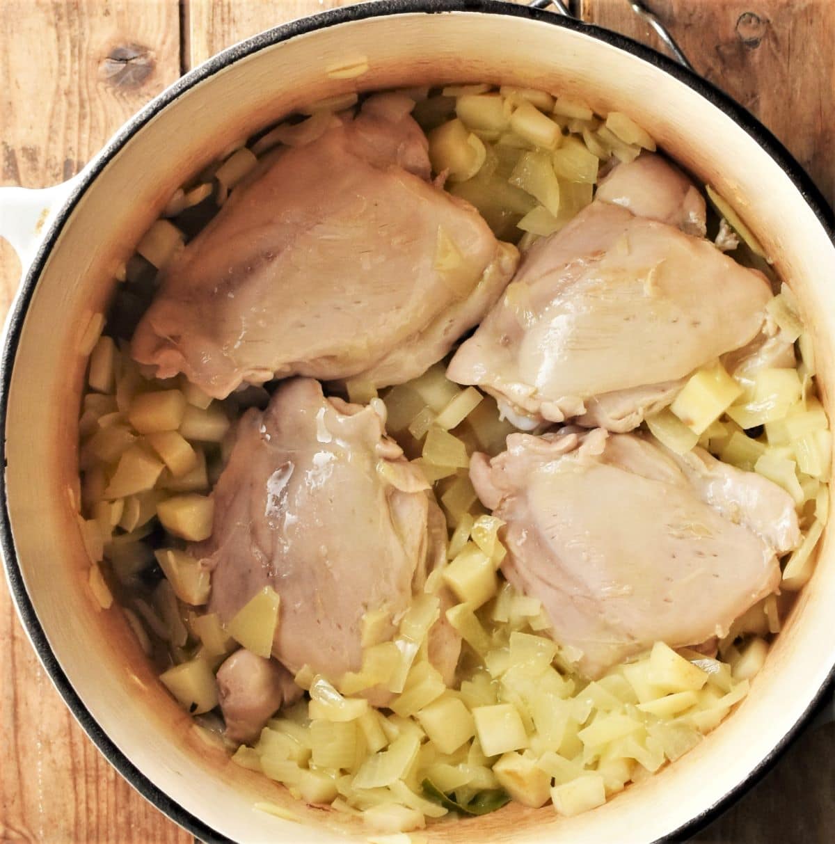 4 skinless chicken thighs with diced vegetables in pot.