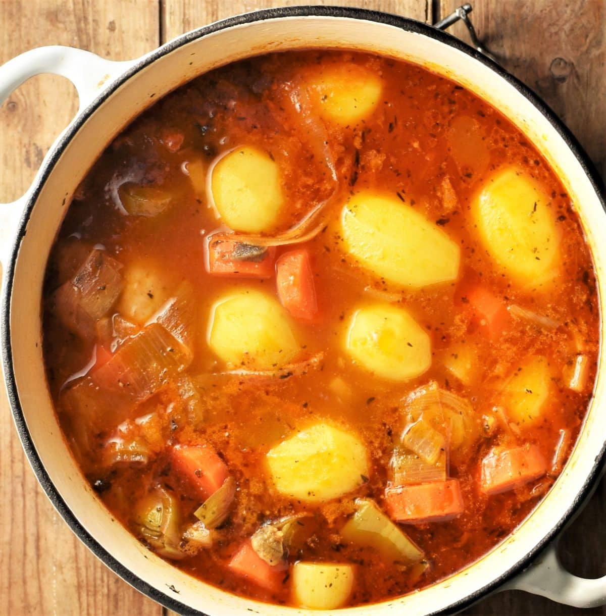 Potato, vegetable and chicken stew in large, white pot.