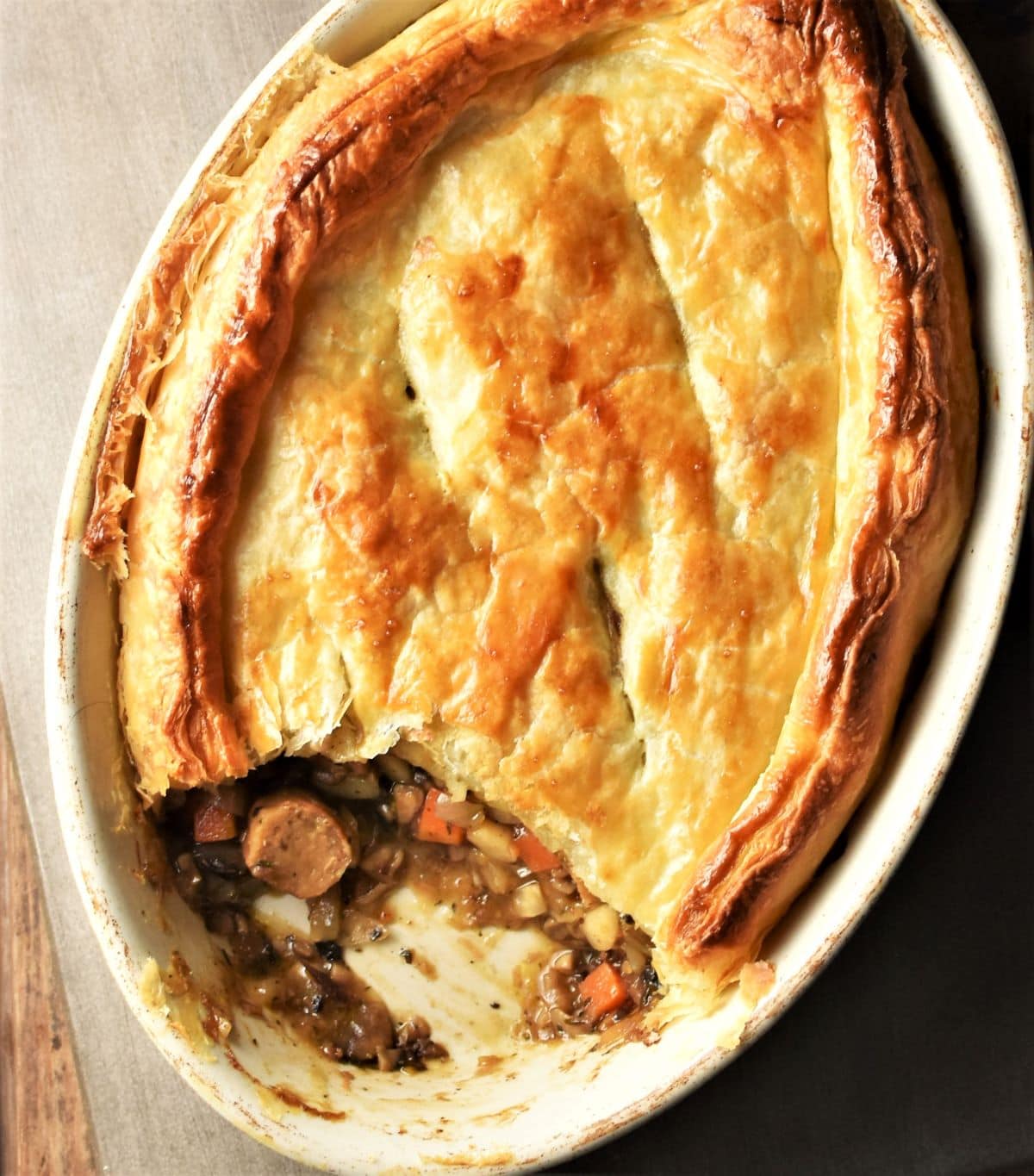 Top down view of sausage pie with puff pastry in oval dish.
