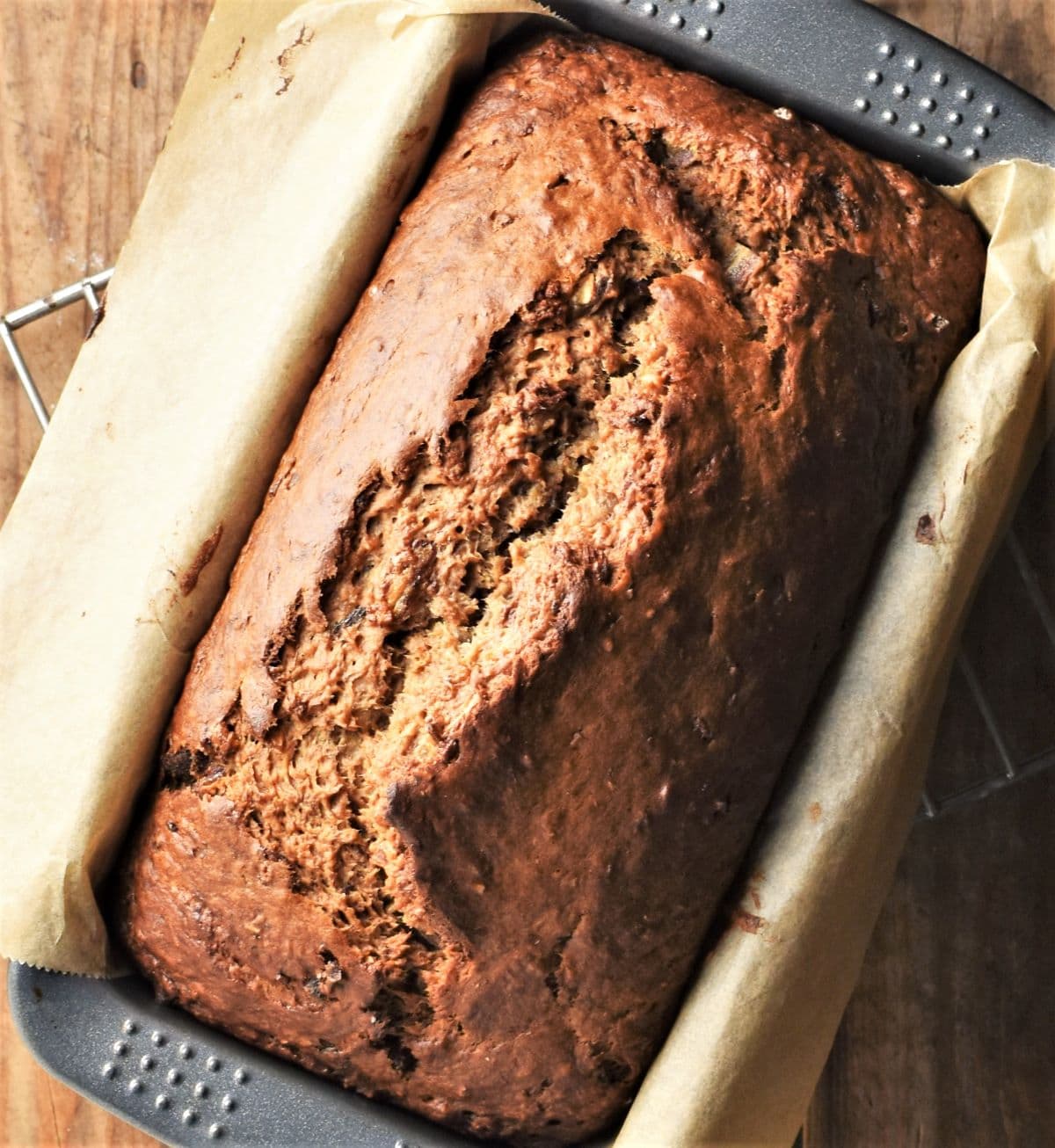 Top down view of banana dates bread in loaf pan lined with parchment.